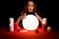 Soothsayer using glowing crystal ball to predict future at table in darkness. Fortune telling Royalty Free Stock Photo