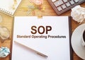 SOP acronym for Standard Operating Procedure, text on white paper next to office accessories on wooden desk Royalty Free Stock Photo