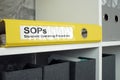 SOP Standard operating procedure concept. A yellow folder lies on an office shelf. Royalty Free Stock Photo