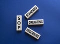 SOP - Standard Operating Procedure symbol. Wooden blocks with word SLA. Beautiful deep blue background. Business and Service Level Royalty Free Stock Photo