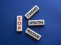 SOP - Standard Operating Procedure symbol. Wooden blocks with word SLA. Beautiful deep blue background. Business and Service Level Royalty Free Stock Photo