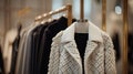 A sophisticated display of a white-gray-black coat and sweater on hangers in a high-end fashion store. These classic