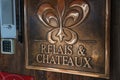 Sophisticated Relais and Chateaux plaque with fleur de lis on wooden surface by modern intercom. Royalty Free Stock Photo