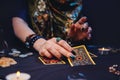 A sorceress lays out fortune-telling cards tarot on the table. Hands close-up. The concept of card reading, magic and esotericism