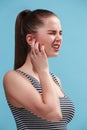 The Ear ache. The sad woman with headache or pain on a blue studio background. Royalty Free Stock Photo