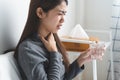 Sore throat in flu season. Young asian woman touching her neck and feeling pain in throat in the bedroom at home