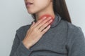 Sore throat in flu season. Young woman touching her neck and feeling pain in throat in the bedroom at home