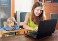 Sorehead mother with baby using laptop