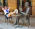 Soria, Spain; 06 24 2019: impolite teenage girl putting her feet on the table of bronze statue of a poet reading a book in front