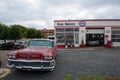 old vintage car in front of a vintage petrol station and workshop