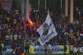 Football supporter singing and waving flags in stadium.