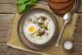 Sorrel soup with cream and eggs, wooden background, top view