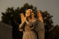 Sorrowful angel with sad face praying to the heaven is the orange morning light at dawn. The century old cemetery statue is heavil Royalty Free Stock Photo