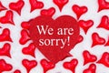 We are sorry message on glitter heart with red hearts on white fabric