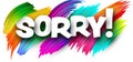 Sorry paper word sign with colorful spectrum paint brush strokes over white