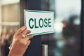 Sorry, were closed. Closeup shot of a young business owner hanging up a close sign on the door of her shop. Royalty Free Stock Photo