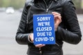 SORRY WERE CLOSED DUE TO COVID-19. Holding blue notebook with text Royalty Free Stock Photo