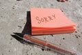 sorry written on an orange sticker and pen on concrete surface