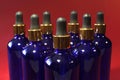 Sorted blue glass bottles with a golden dropper on a red background