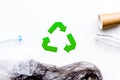 Sorting waste and recycle. Green paper recycling sign among waste paper, plastic, glass, polyethylene on white Royalty Free Stock Photo