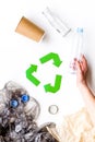 Sorting waste and recycle. Green paper recycling sign among waste paper, plastic, glass, polyethylene on white Royalty Free Stock Photo