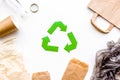 Sorting waste and recycle. Green paper recycling sign among waste paper, plastic, glass, polyethylene on white Royalty Free Stock Photo