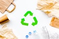 Sorting waste and recycle. Green paper recycling sign among waste paper, plastic, glass, polyethylene on white