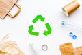 Sorting waste and recycle. Green paper recycling sign among waste paper, plastic, glass, polyethylene on white Royalty Free Stock Photo