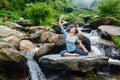 Sorty fit woman doing yoga asana outdoors at tropical waterfall Royalty Free Stock Photo