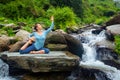 Sorty fit woman doing yoga asana outdoors at tropical waterfall Royalty Free Stock Photo