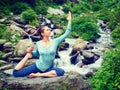 Sorty fit woman doing yoga asana outdoors at tropical waterfall Royalty Free Stock Photo