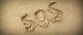 SOS abbreviation written on a wide sand background Royalty Free Stock Photo