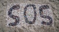 SOS message on the beach with stones and shells Royalty Free Stock Photo