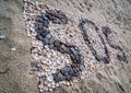 SOS message on the beach with stones and shells