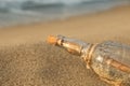 SOS message in glass bottle on sand, closeup Royalty Free Stock Photo