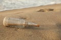 SOS message in glass bottle on sand near sea, space for text Royalty Free Stock Photo