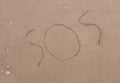 SOS signal text written on sand background Royalty Free Stock Photo