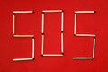 SOS. SOS distress signal icon laid out of matches on a red background. Inscription pine red background. Royalty Free Stock Photo