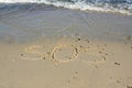 SOS - word drawn on the sand beach with the soft wave. Royalty Free Stock Photo