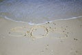 SOS - word drawn on the sand beach with the soft wave. Royalty Free Stock Photo