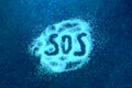 SOS word hand written on white powder, distress signal