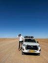 Car on gravel road in desert. Sandy landscape. Toyota Hilux. Man driver.