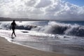 Silhouette of girl walking along the beach with waves and water splashes on holidays, blue sea, waves sun light background