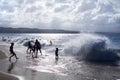 Silhouettes of children and people playing on the beach in the waves and water splashes on holidays, blue sea, waves sun light