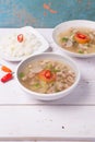 Soto or coto or indonesian beef soup served with white rice, tomato, soy, and green onion