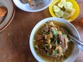 Soto Daging Sapi. Indonesian Food in a white bowl. Served on the wooden table. Traditional Beef in a clear soup.