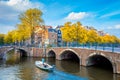 Soul of Amsterdam. Beautiful autumn, golden falling leaves, old sloping houses, bridges, canals and a boat. Autumn day in Royalty Free Stock Photo