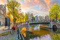 Soul of Amsterdam. Early morning in Amsterdam. Ancient houses, bridges, traditional bicycles, canals and the sun shines through Royalty Free Stock Photo