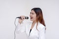 A soulful young woman singing into a microphone while facing sideways. Isolated on a white background