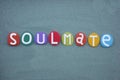 Soulmate word composed with multi colored stone letters over green sand